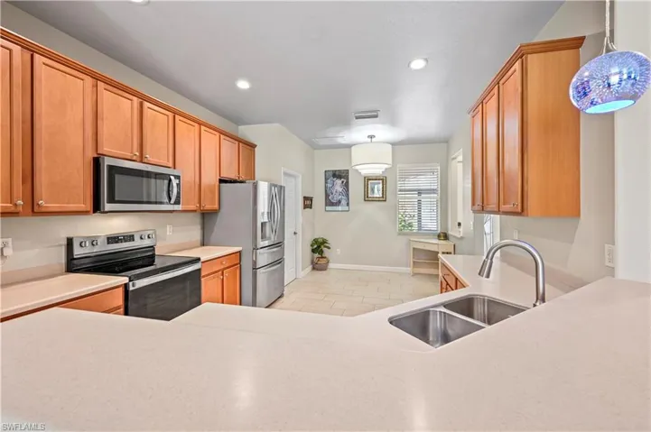 Kitchen with stainless steel appliances, sink, and decorative light fixtures
