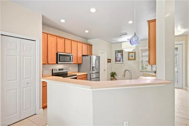 Kitchen featuring sink, kitchen peninsula, light tile floors, and appliances with stainless steel finishes
