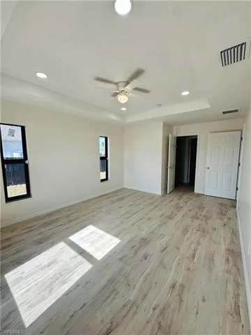 Spare room featuring light wood-type flooring, a raised ceiling, and ceiling fan