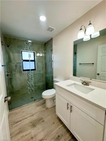 Bathroom with vanity, hardwood / wood-style flooring, toilet, and walk in shower