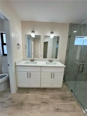 Bathroom featuring vanity, toilet, and a shower with shower door