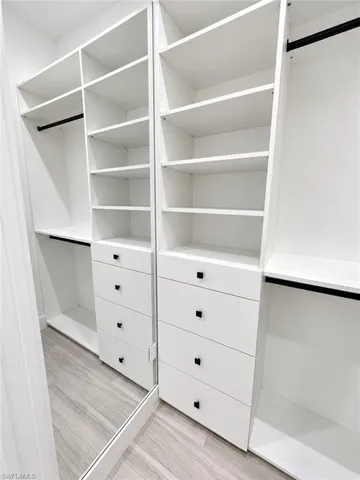 Custom closet system with multiple shelving units, integrated drawers featuring black hardware, and dedicated hanging rods