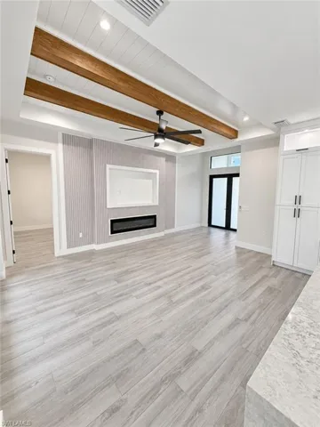 Coffered ceiling with wood beams and shiplap inlay, wood-finish flooring, built-in fireplace, built-in cabinetry, and black-framed French doors