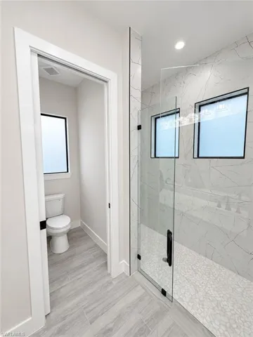 Walk-in shower with clear glass enclosure and contrasting tile finishes