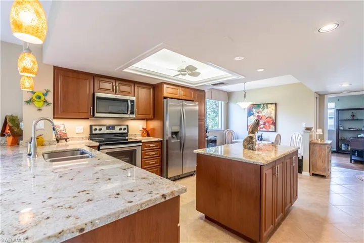 Kitchen with island, tray ceiling, stainless appliances, light countertops and plenty of cabinet space