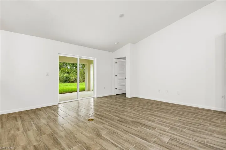 Empty room with wood tiled floors and vaulted ceiling