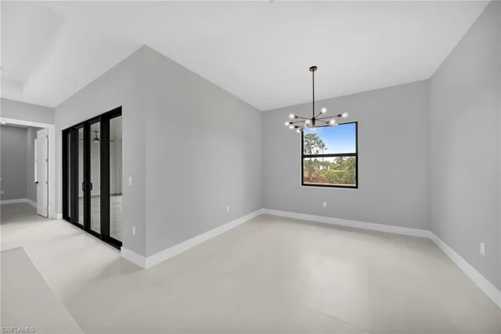 Empty room featuring a chandelier and baseboards