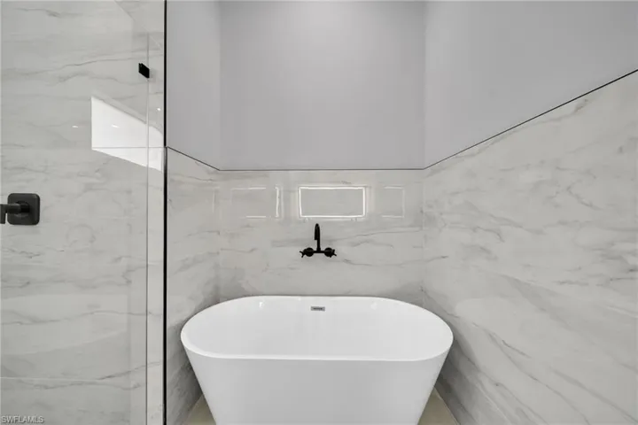 Full bath featuring a soaking tub and marble tiled floors