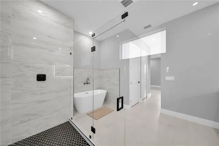 Full bathroom with a soaking tub, a marble finish shower, and a closet