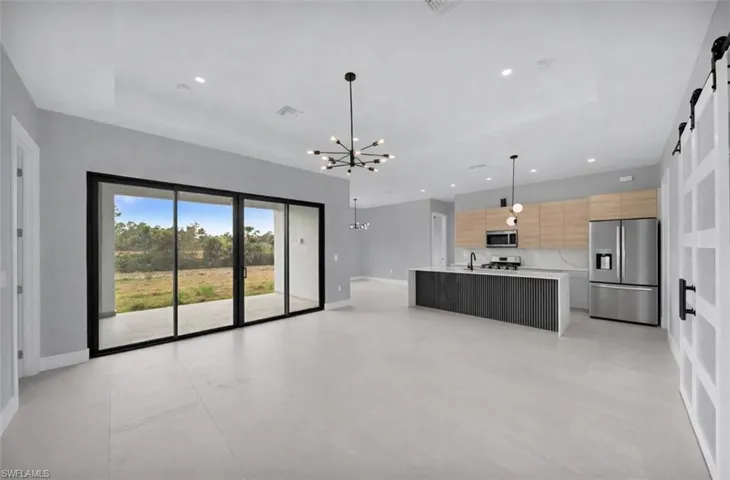 Kitchen with a barn door, pendant lighting, appliances with stainless steel finishes, a chandelier, and open floor plan