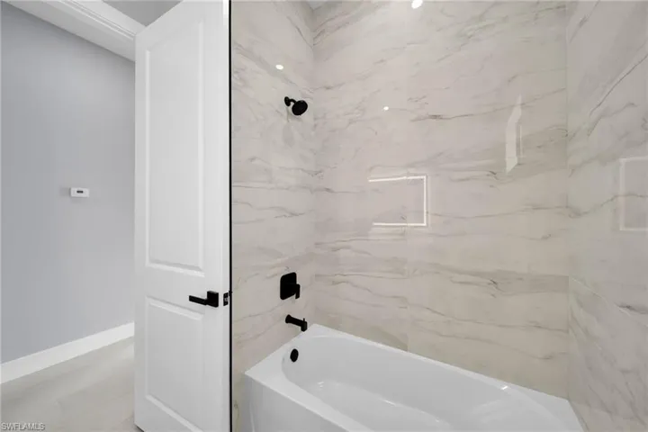 Full bath with a combined bath / shower with marble appearance and baseboards