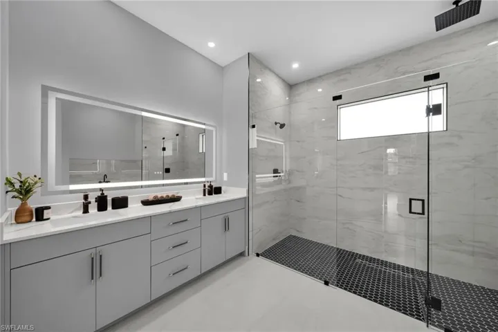Bathroom with double vanity, a marble finish shower, and recessed lighting