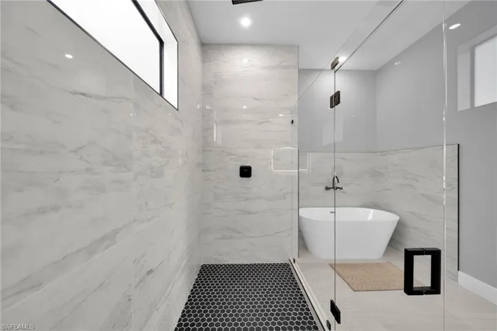 Bathroom with a marble finish shower, a freestanding tub, and tile patterned floors
