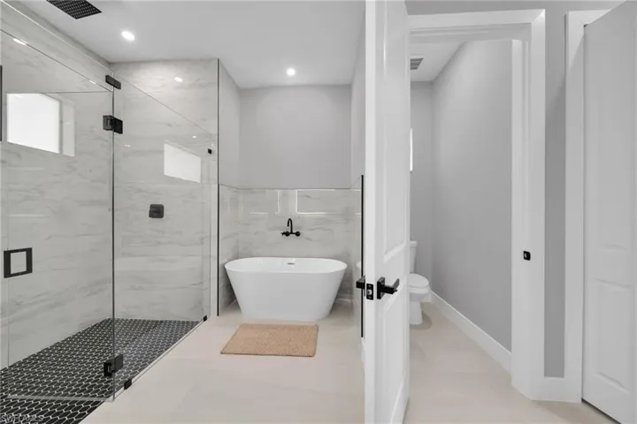Bathroom with a freestanding tub, a marble finish shower, and recessed lighting