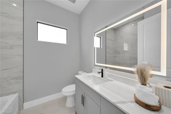 Full bathroom with vanity, plenty of natural light, a bath, and a marble finish shower