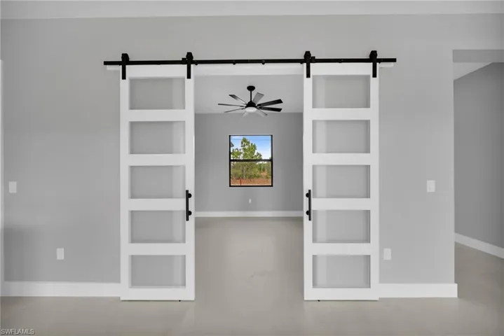Unfurnished room with a barn door, built in shelves, and a ceiling fan