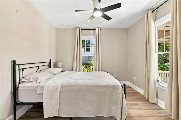3rd bedroom with wood-plank tile flooring, white trim, a ceiling fan with integrated lighting, and multiple windows.