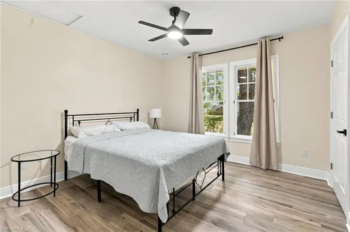 2nd bedroom with wood-plank tile flooring, white trim, a ceiling fan with integrated lighting,, multiple windows and a closet.