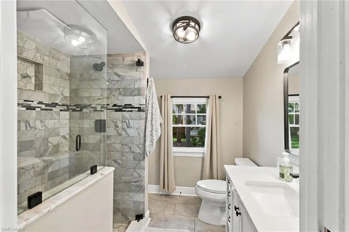 Master bathroom with a glass-enclosed shower with tiled walls and a decorative mosaic band