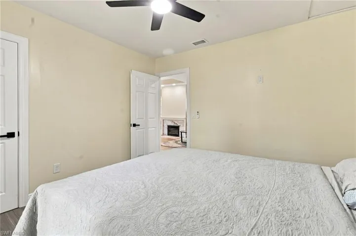 2nd bedroom with wood-plank tile flooring, white trim, a ceiling fan with integrated lighting,, multiple windows and a closet.