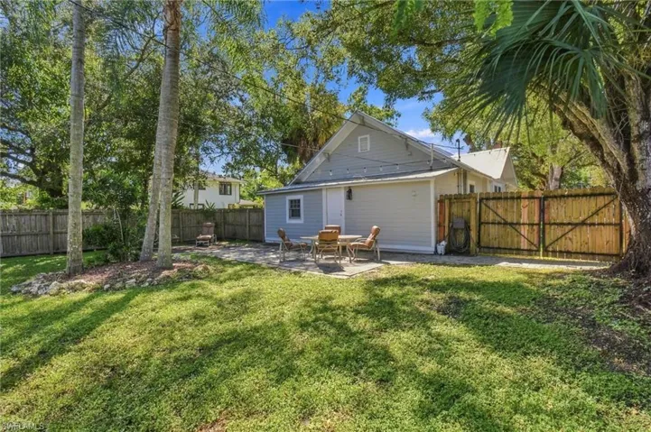 Expansive fenced in backyard with mature tress, a manicured lawn, established trees, and a paver patio.