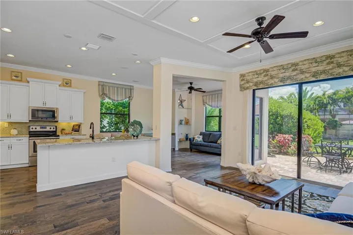 Living area with crown molding, recessed lighting, ceiling fan, and dark wood-type flooring