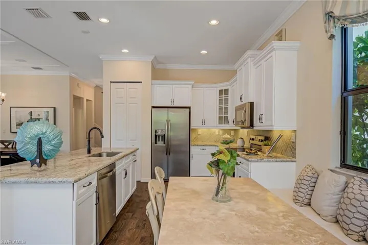Kitchen with appliances with stainless steel finishes, crown molding, white cabinets, an island with sink, and recessed lighting