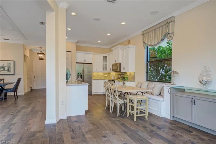Kitchen with backsplash, crown molding, glass insert cabinets, stainless steel appliances, and dark wood finished floors