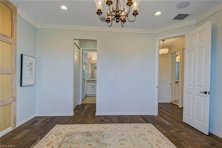 Unfurnished bedroom featuring a chandelier, recessed lighting, wood finished floors, and ensuite bath