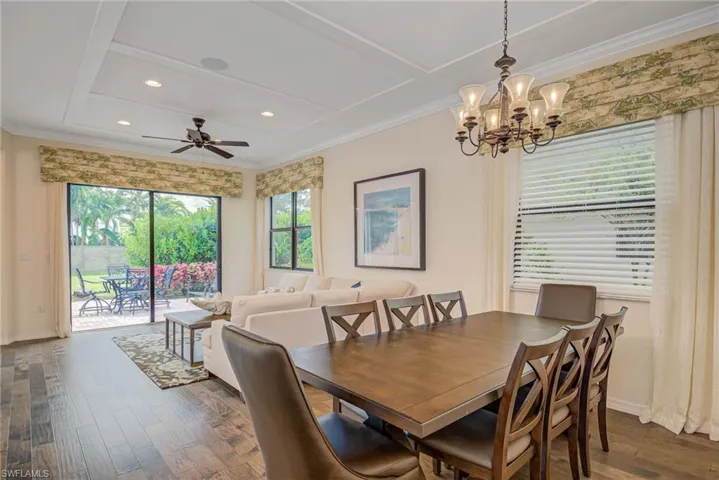 Dining space featuring dark wood finished floors, recessed lighting, ornamental molding, a chandelier, and a ceiling fan
