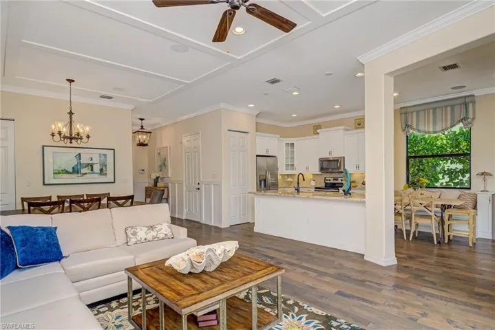 Living room with ornamental molding, dark wood-type flooring, a chandelier, ceiling fan, and recessed lighting