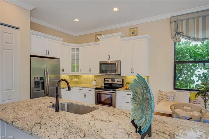 Kitchen with stainless steel appliances, crown molding, white cabinets, decorative backsplash, and recessed lighting
