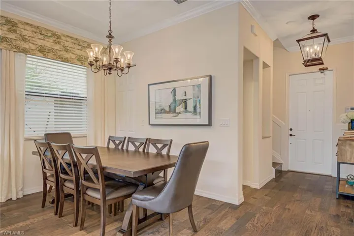 Dining room featuring a chandelier, crown molding, and dark wood-style floors