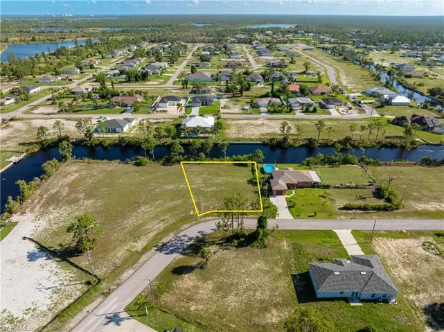Aerial view of residential area featuring a nearby body of water and property parcel outlined