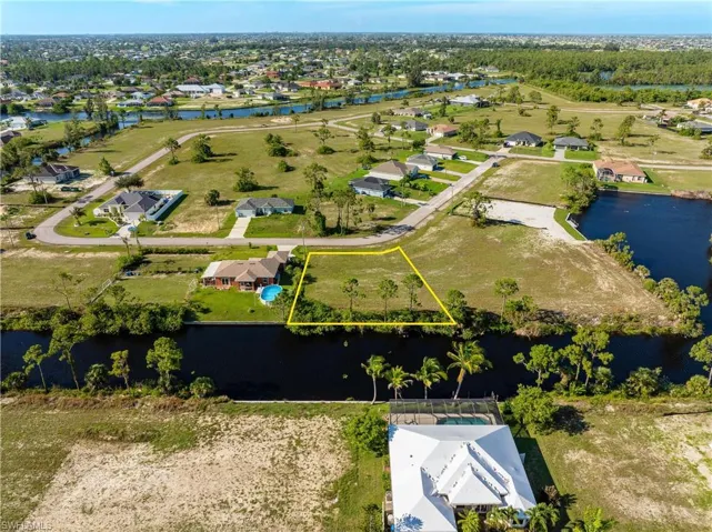 Aerial perspective of suburban area featuring property parcel outlined and a nearby body of water