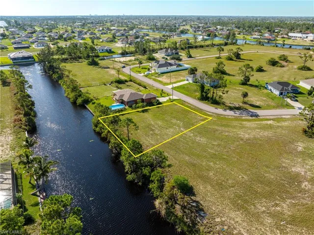 Aerial perspective of suburban area featuring a nearby body of water and property parcel outlined