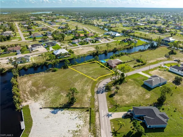Aerial view of residential area featuring property boundaries highlighted and a nearby body of water
