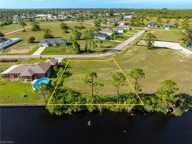 Aerial view of residential area with a large body of water and property parcel outlined