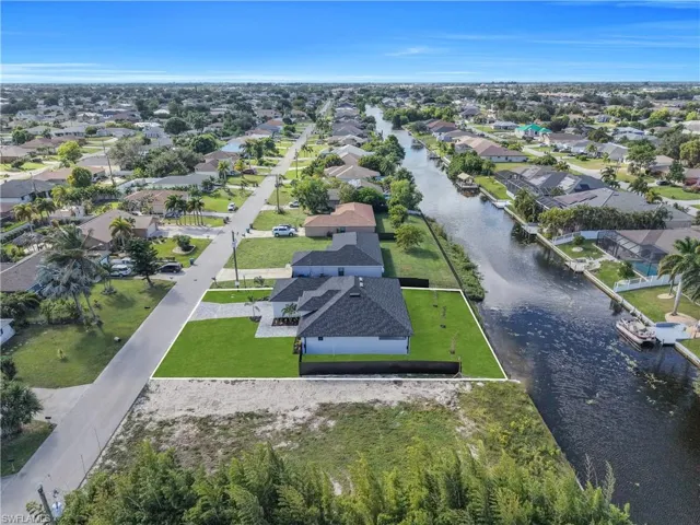 Waterfront residential lot featuring canal frontage, a paved driveway, and established landscaping