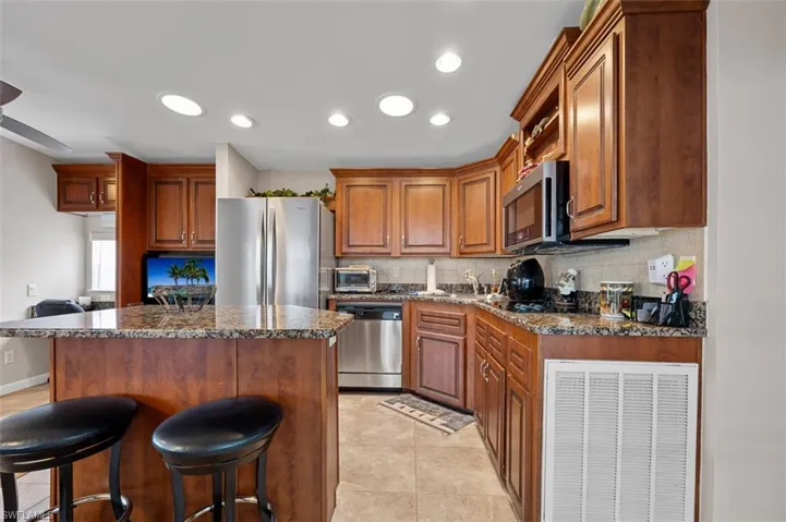 Kitchen featuring appliances with stainless steel finishes, backsplash, a kitchen island, and dark stone counters
