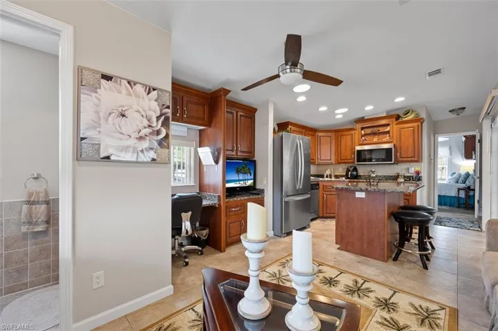 Kitchen featuring ceiling fan, a center island, stainless steel appliances, a kitchen bar, and light tile patterned flooring
