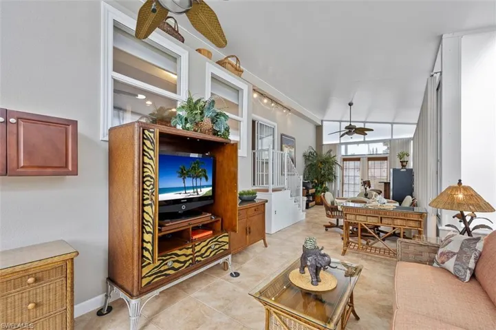 Living room featuring vaulted ceiling, ceiling fan, light tile patterned floors, and french doors