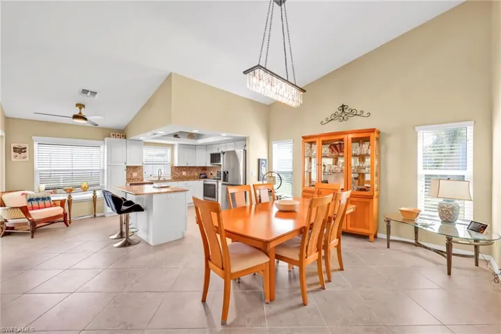 Dining room with visible vents, high vaulted ceiling, a wealth of natural light, and light tile patterned floors