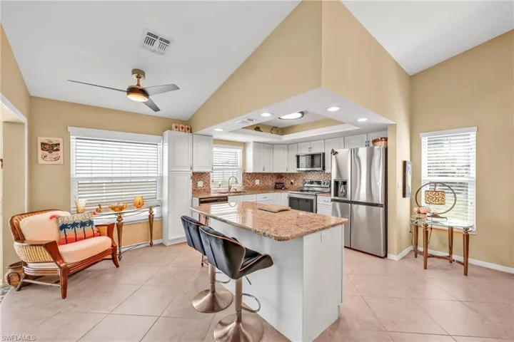 Kitchen featuring a sink, visible vents, a ceiling fan, light stone countertops, and appliances with stainless steel finishes