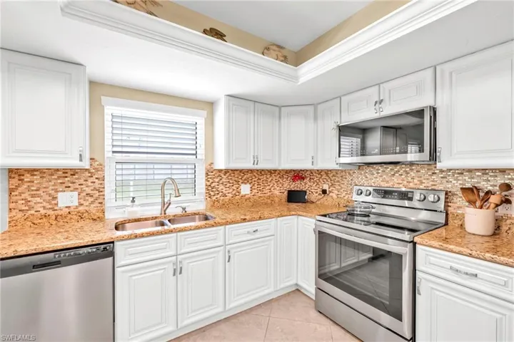 Kitchen with white cabinetry, stainless steel appliances, light tile patterned flooring, and a sink