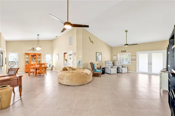 Living area with visible vents, a ceiling fan, light tile patterned floors, french doors, and high vaulted ceiling