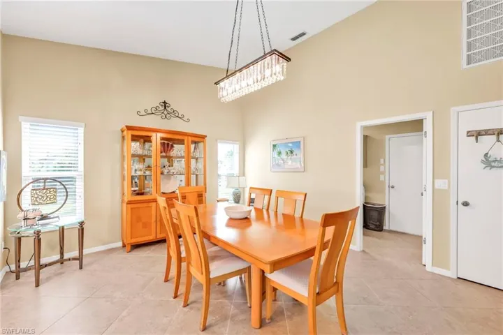 Dining room with visible vents, a high ceiling, baseboards, and light tile patterned floors