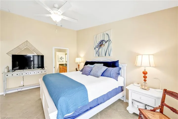 Bedroom with a ceiling fan, ensuite bath, and light tile patterned flooring