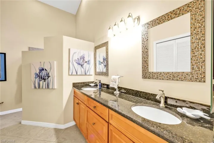 Full bathroom with double vanity, tile patterned flooring, baseboards, and a sink