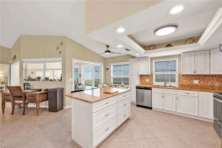 Kitchen featuring tasteful backsplash, light stone countertops, stainless steel dishwasher, and a sink